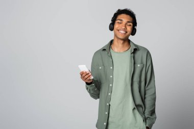 Akıllı telefonlu Afro-Amerikan bir adam Grey 'de el ele tutuşup müzik dinliyor.