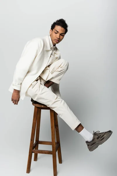 Молодий Афроамериканський Чоловік Модному Костюмі Кросівки Позує Високому Табуреті Сірому — стокове фото