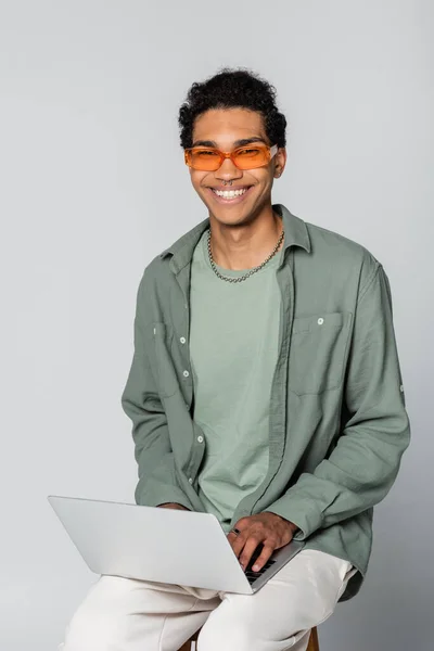 Happy African American Man Orange Eyeglasses Looking Camera Typing Laptop — Stock Photo, Image