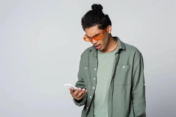 Shocked African American Man Orange Eyeglasses Looking Cellphone Isolated Grey — Stock Photo, Image