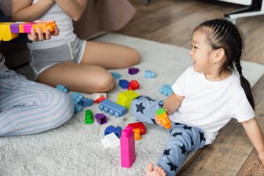 Ebeveynler mutlu Asyalı kızlarıyla yapı taşı oynuyorlar 