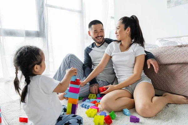 快乐的亚洲丈夫和妻子相互望着对方 蹒跚学步的女儿玩积木游戏 — 图库照片