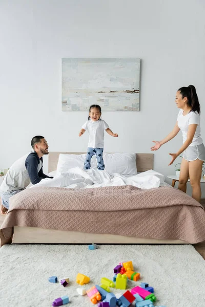 Felice Asiatico Genitori Guardando Bambino Figlia Jumping Letto — Foto Stock