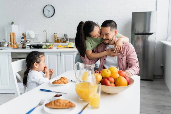 Asian Wife Kissing Husband While Daughter Eating Strawberry Breakfast — Stock Photo, Image