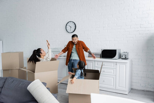 asian woman and kid in boxes scaring man in new home 