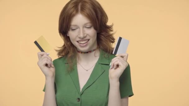 快乐的红头发少女 手里拿着用黄色隔开的信用卡 — 图库视频影像