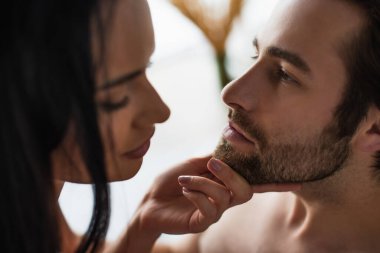 Esmer kadın sakallı adamın çenesine dokunuyor.