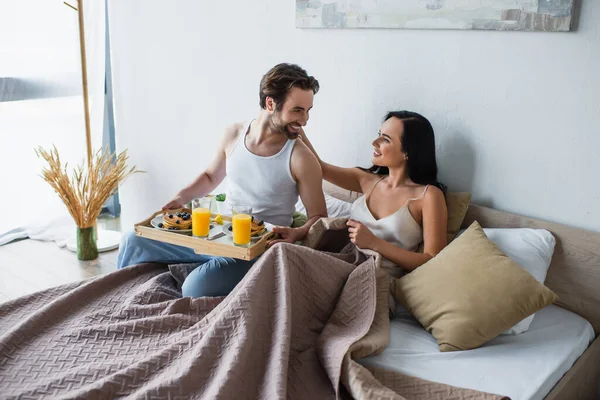 Bearded Man Holding Breakfast Tray Looking Cheerful Girlfriend Bed — 스톡 사진