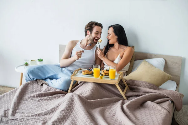 Mulher Alegre Alimentando Namorado Com Panquecas Saborosas Cama — Fotografia de Stock