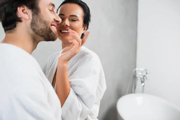 Mujer Alegre Aplicando Crema Facial Nariz Del Novio Sonriente Albornoz — Foto de Stock