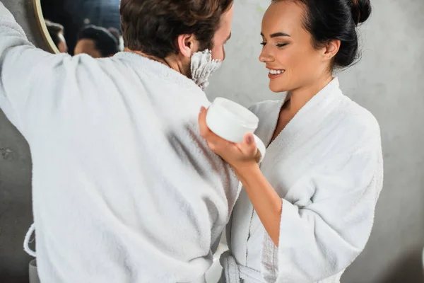 Mujer Alegre Sosteniendo Contenedor Con Crema Facial Cerca Hombre Feliz — Foto de Stock