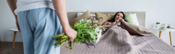 Homem Segurando Buquê Flores Perto Namorada Deitada Cama Banner — Fotografia de Stock