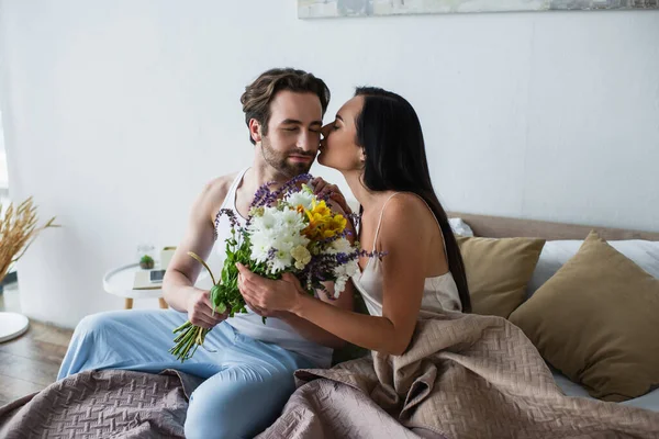 Woman Kissing Cheek Man Holding Bouquet Flowers Bedroom — Stock Photo, Image