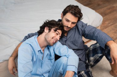 cheerful man leaning on shoulder of boyfriend at home clipart