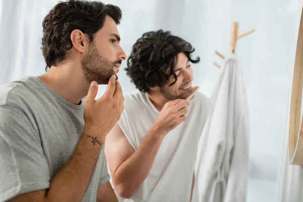 Tattooed Man Touching Face While Boyfriend Brushing Teeth Blurred Background — Stock Photo, Image