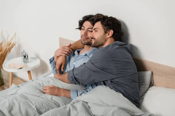 Alegre Gay Casal Sorrindo Enquanto Abraçando Cama Casa — Fotografia de Stock