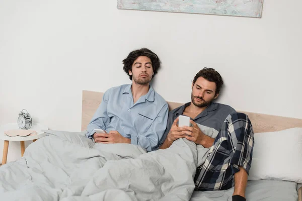 Homem Olhando Para Celular Enquanto Namorado Conversando Cama — Fotografia de Stock