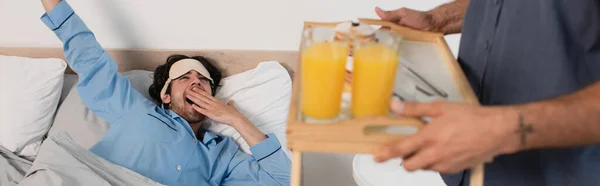 Man Eye Mask Yawning Blurred Boyfriend Holding Tray Orange Juice — Stock Photo, Image