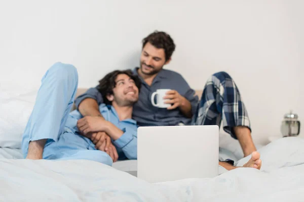 Wazig Gelukkig Gay Paar Kijken Naar Elkaar Buurt Laptop Bed — Stockfoto