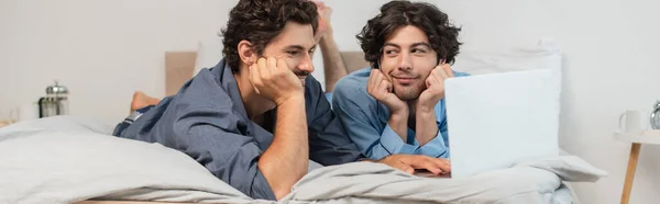 Complacido Pareja Gay Viendo Película Ordenador Portátil Dormitorio Bandera —  Fotos de Stock