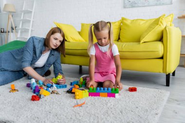 özel anaokulu öğretmeni anaokulu kızıyla bina blokları oynuyor.