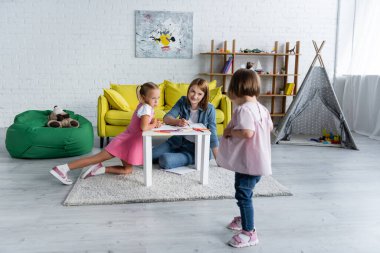 Neşeli anaokulu öğretmeni ve anaokulu kızı Down sendromlu bulanık bir çocuğa bakıyor. 