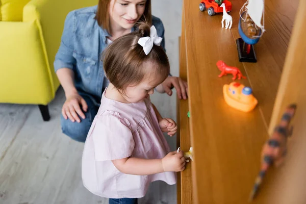 Menina Criança Com Síndrome Olhando Para Brinquedos Prateleira Madeira Perto — Fotografia de Stock