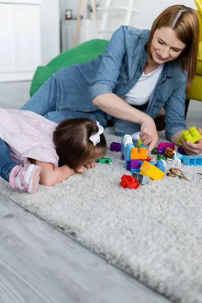 Kleinkind Mit Syndrom Spielt Mit Glücklicher Kindergärtnerin Auf Teppich — Stockfoto