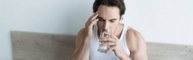unwell man touching head and drinking water while suffering from migraine, banner clipart