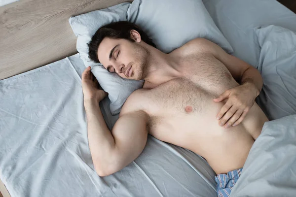 青い枕の上でベッドで寝てる若者 — ストック写真