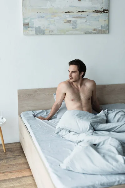 Shirtless Man Sitting Bed Blue Blanket Looking Away — Stock Photo, Image