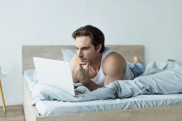 Young Man Thinking While Using Laptop Bed — Stock Photo, Image