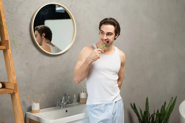 洗澡间靠近水槽处的白色水槽顶部刷牙的男人 — 图库照片