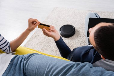 Bilgisayarında robot elektrik süpürgesinin yanında kredi kartı olan bulanık bir çift. 