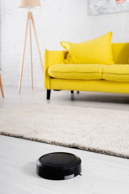 Robotik süpürge oturma odasındaki halının yanında. 