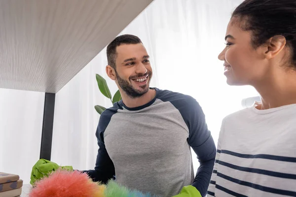 Interracial Couple Smiling Each Other While Cleaning Cupboard — Stock Photo, Image