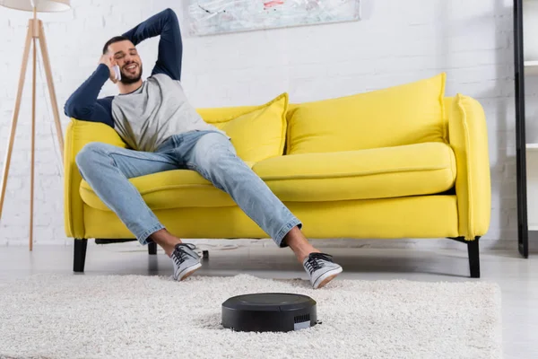 Staubsauger Auf Teppich Neben Verschwommenem Mann Der Mit Smartphone Spricht — Stockfoto