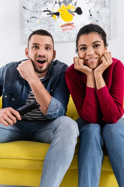 Opgewonden Interraciaal Paar Met Afstandsbediening Zoek Naar Camera — Stockfoto