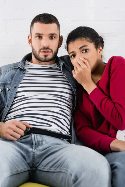 Mujer Afroamericana Asustada Mirando Cámara Cerca Novio Con Controlador Remoto —  Fotos de Stock