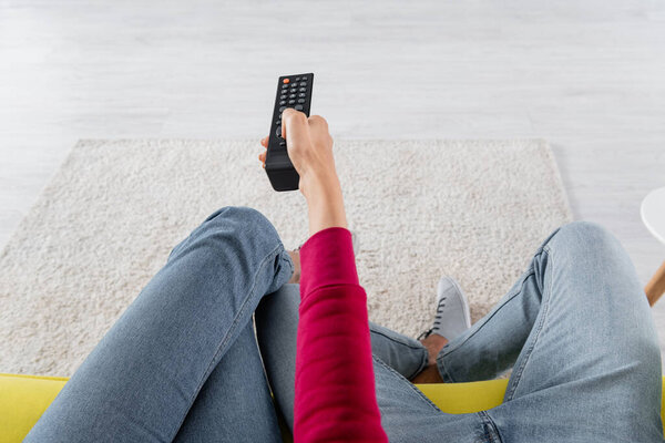 Cropped view of woman clicking channels near boyfriend on couch 