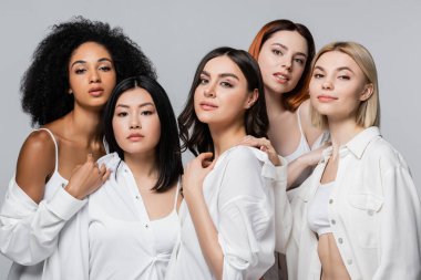 Asyalı ve kıvırcık Afrikalı beyaz tişörtlü Amerikan modelleri, gri tişörtlü kadınlara poz veriyor.