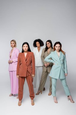 Gri üzerine izole edilmiş şık takım elbiseli çok ırklı modellerin tam uzunluğu