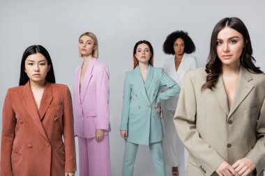 Gri üzerine izole edilmiş şık takım elbiseli ırklar arası modeller.