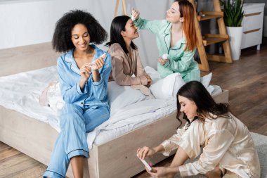 Mutlu kızıl kadın, Asyalı arkadaşına pamuklu ped ile toner sürüyor. 