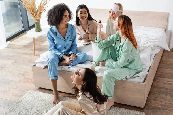 Roodharige Vrouw Tonen Nagellak Naar Vrolijke Interraciale Vrienden Tijdens Pyjamafeest — Stockfoto