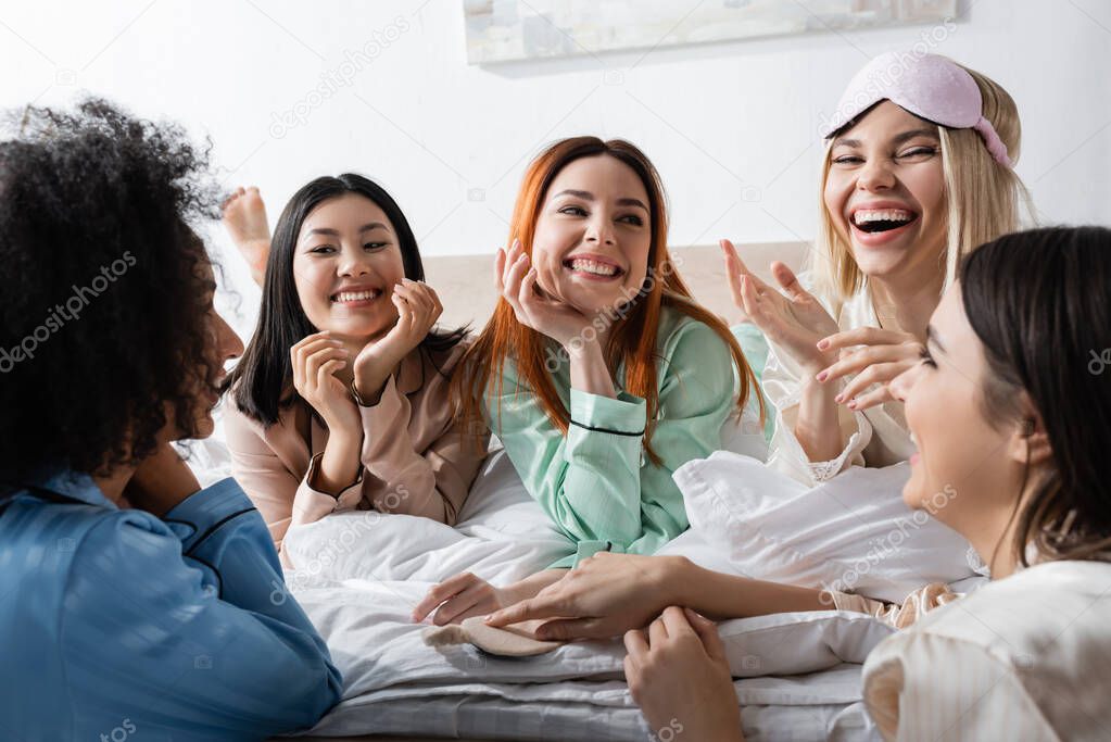 group of happy multiethnic women talking and laughing during slumber party 