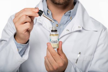 Beyaz üzerinde izole edilmiş kenevir yağı şişesi olan hekimin kısmi görüşü
