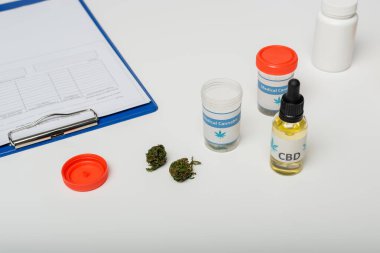 containers with medication made from medical cannabis near clipboard with prescription on white desk clipart