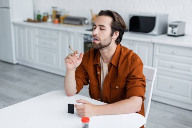 Evdeki çakmak ve kavanozun yanında tıbbi esrar içen adam 