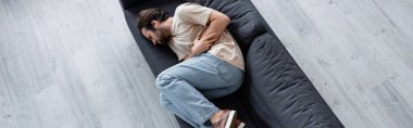 Top view of man suffering from bellyache on couch, banner  clipart
